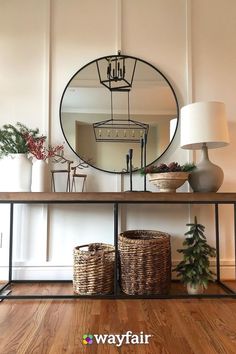 a mirror sitting on top of a wooden shelf next to a table with baskets under it