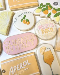 some decorated cookies are sitting on a white tablecloth with oranges and lemons