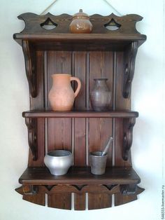 an old wooden shelf with vases and pitchers on it