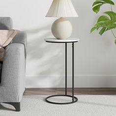 a white lamp sitting on top of a table next to a gray couch