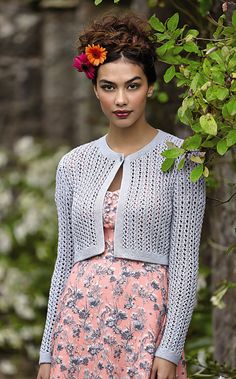 a woman standing in front of a tree wearing a pink dress and cardigan sweater