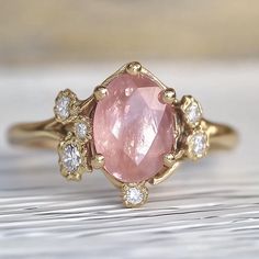 a pink diamond ring sitting on top of a wooden table