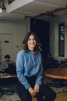 a woman sitting on top of a wooden table