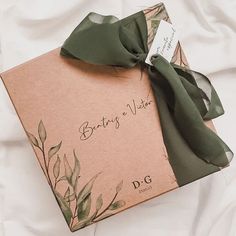 an open box with a green ribbon tied around it on top of a white sheet