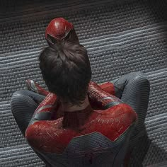 a woman in a spiderman costume sitting on a couch with her back to the camera