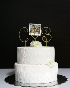 a wedding cake with a photo on top and two white flowers in the bottom tier