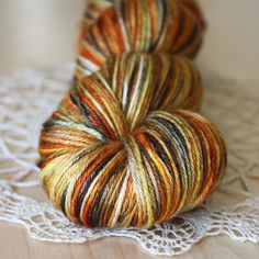 two skeins of yarn sitting on top of a doily