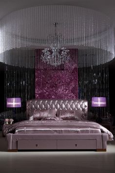 a bedroom with a chandelier hanging from the ceiling and a pink bed in front of it