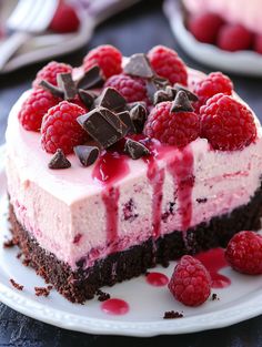 a piece of cake with raspberries and chocolate chips on top is sitting on a plate