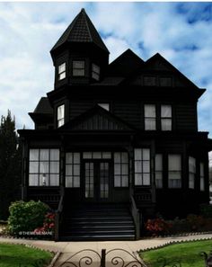 a large black house with lots of windows on it's front porch and stairs leading up to the second floor