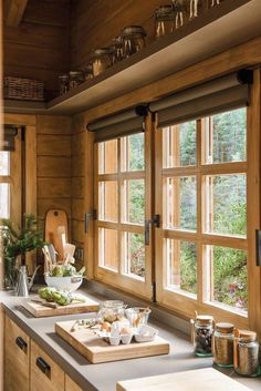 a kitchen counter with cutting boards and utensils in front of the open windows