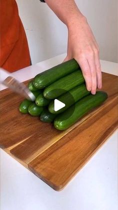 a person chopping cucumbers on a cutting board