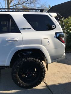 a white four door suv parked in front of a house