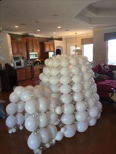 a large group of white balloons are in the middle of a living room and kitchen