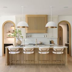 a large kitchen with wooden cabinets and white counter tops, along with two hanging lights over the island