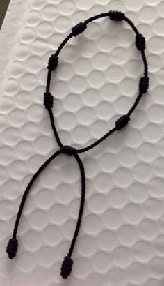 a black beaded necklace on a white surface