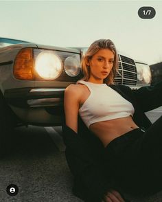 a woman sitting on the ground next to a car