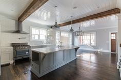 a large kitchen with an island in the middle and wood flooring on the other side