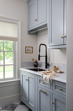 a kitchen with gray cabinets and marble counter tops