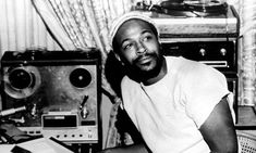 a black and white photo of a man sitting in front of a desk with sound equipment