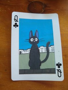 a playing card with a black cat on it's front and back sides, sitting on top of a wooden table