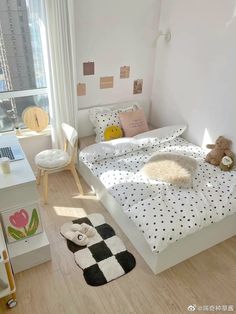 a white bed with black and white polka dot sheets in a bedroom next to a window