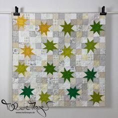 a green and yellow star quilt hanging on a wall