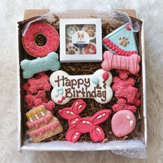 a box filled with lots of decorated cookies and pastries on top of a white blanket