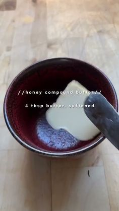 a person is using a knife to cut cheese into small pieces in a bowl on a wooden table