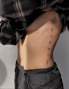 the back of a woman's stomach with a small tattoo on her left side