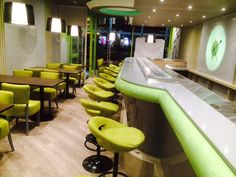 the interior of a restaurant with green and yellow chairs, bar stools and counters