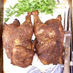 two pieces of meat sitting on top of a pan next to a knife and fork