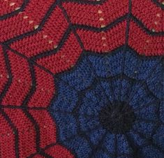 a close up view of a red and blue crocheted spider web