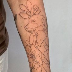 a person with a tattoo on their arm that has flowers and a deer in it