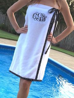 a woman standing in front of a pool wearing a white towel with the word monogram on it