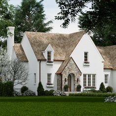 a large white house with two story windows and brown shingles on the roof is surrounded by green grass