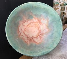 a green bowl sitting on top of a wooden table