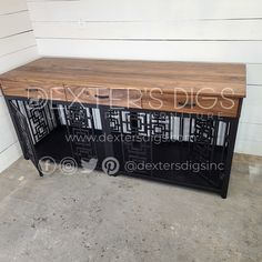 a wooden table with metal and wood accents on the top, in front of a white wall