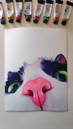 a painting of a cat's face with six different colored paint tubes next to it