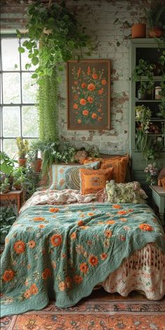 a bed with flowers on it in front of a brick wall and potted plants