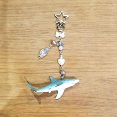 a keychain with a shark and star charm on it's side hanging from a wooden table