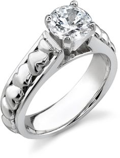 a white gold engagement ring with an oval cut diamond in the center and hearts on the band