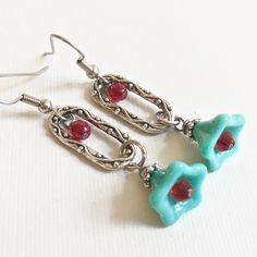 "Turquoise Red Earrings - Turquoise Czech Glass Flowers with Antiqued Silver Plated Beadcaps dangle from Decorative Antiqued Silver plated Pewter Ovals embellished with Czech Glass Red Crystals. The throat of the Turquoise flowers have Red Glass Crystals. Surgical Steel Earwires Earrings measure 2\" from top of earwires to bottom of flowers." Red Whimsical Nickel-free Earrings, Whimsical Red Nickel-free Earrings, Whimsical Red Drop Earrings, Unique Nickel-free Drop Flower Earrings, Whimsical Red Jewelry With Matching Earrings, Unique Nickel-free Dangle Flower Earrings, Unique Nickel Free Dangle Flower Earrings, Whimsical Handmade Red Earrings, Whimsical Turquoise Nickel-free Earrings