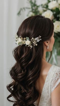 a woman with long brown hair wearing a white flowered headpiece in front of flowers