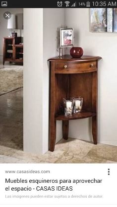 a small wooden table with an apple on top in the corner next to a wall