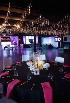 an empty dance floor is decorated with pink and black table cloths, white centerpieces, and candles