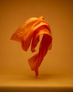 an orange cloth blowing in the wind on a yellow background with room for text or image