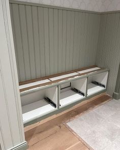 an empty room with some white shelves and wood paneling on the wall behind it