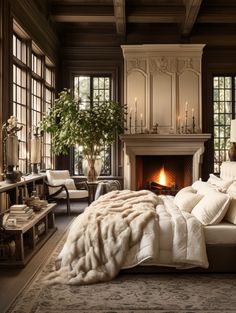 a large bedroom with a fireplace and lots of windows on the wall, along with a bed covered in white blankets