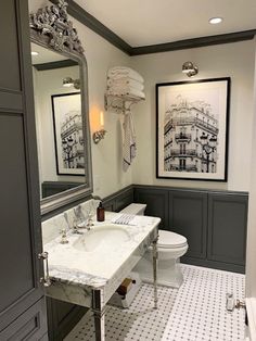 a white toilet sitting next to a sink in a bathroom under a large framed mirror